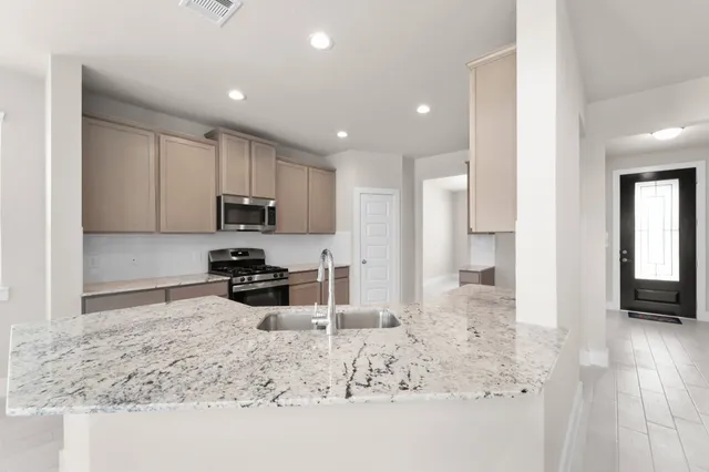 a kitchen with granite countertop sink and refrigerator