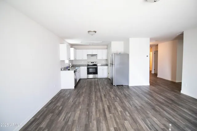 a view of an empty room with wooden floor and closet