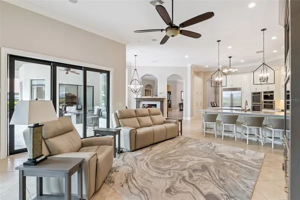 a living room with furniture a ceiling fan a flat screen tv and a large window