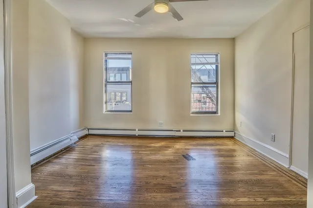 a view of an empty room with window and wooden floor