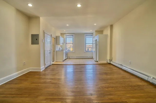 a view of empty room with wooden floor and fan