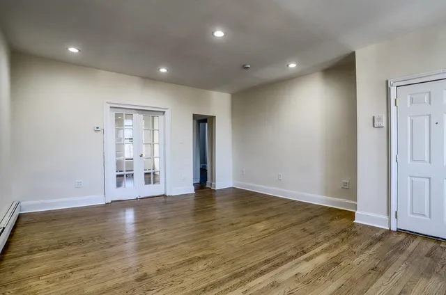 a view of an empty room with wooden floor and closet
