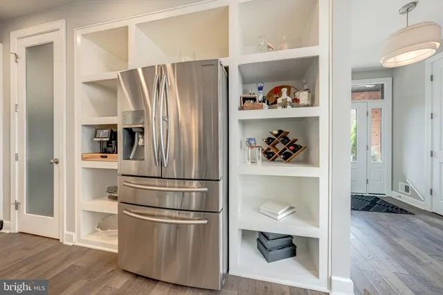 a kitchen with refrigerator and wooden floor