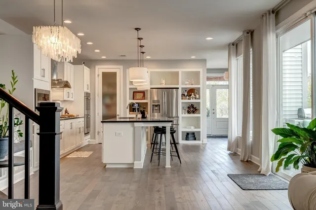 a open kitchen with stainless steel appliances granite countertop a refrigerator a stove a sink dishwasher and a dining table with wooden floor