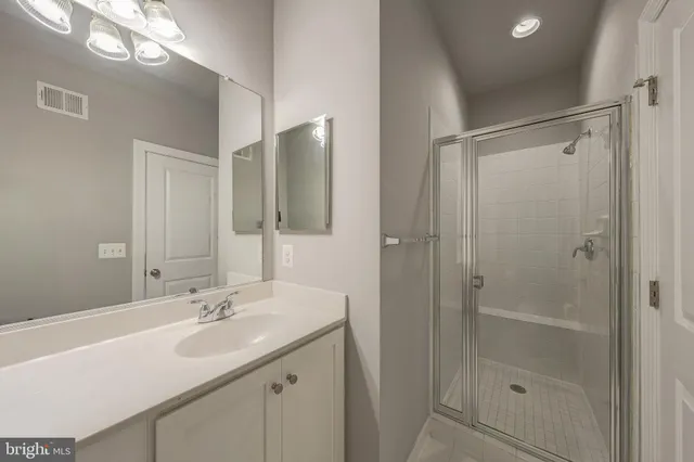 a bathroom with a shower sink vanity and mirror