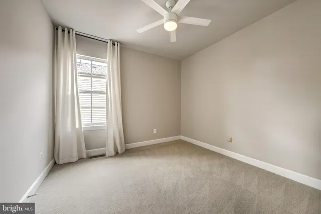an empty room with a chandelier fan and windows