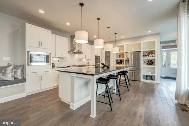 a kitchen with stainless steel appliances kitchen island granite countertop a table chairs stove and white cabinets
