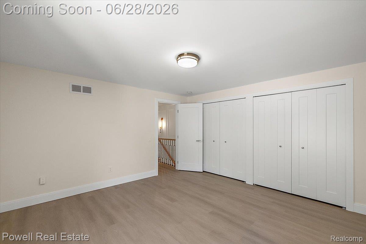 1447 Ravineview Court, Unit C12 Bloomfield Hills, MI 48304 - Photo 41 of 49 Spacious room featuring light wood-finish flooring, ample closet storage with bi-fold doors, white baseboards, and a flush-mount ceiling light fixture