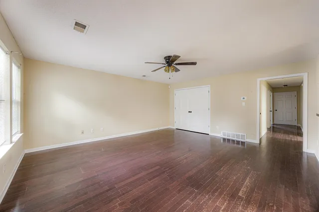 an empty room with wooden floor and windows