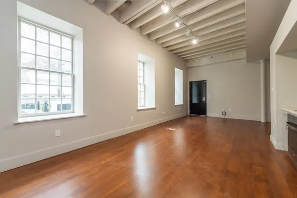 an empty room with wooden floor and windows