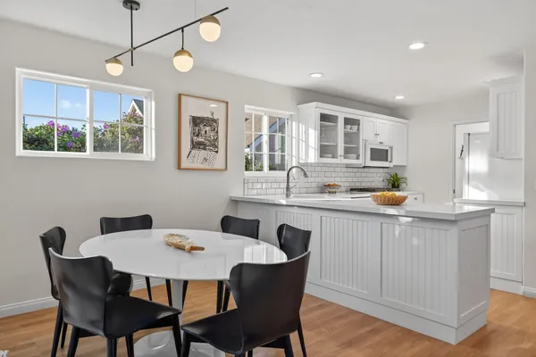 a kitchen with stainless steel appliances granite countertop a dining table chairs and wooden floor