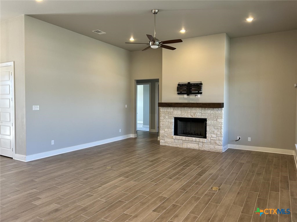 6426 Clayton Court Temple, TX 76502 - Photo 12 of 34 an empty room with wooden floor a fireplace and a window