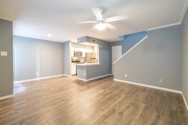 an empty room with wooden floor fan and windows
