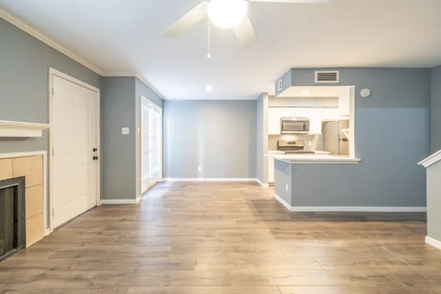 a view of an empty room with window and wooden floor