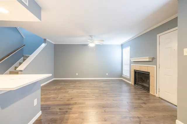a view of an empty room with wooden floor and a fireplace