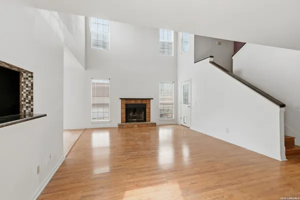 a view of an empty room with wooden floor and a fireplace