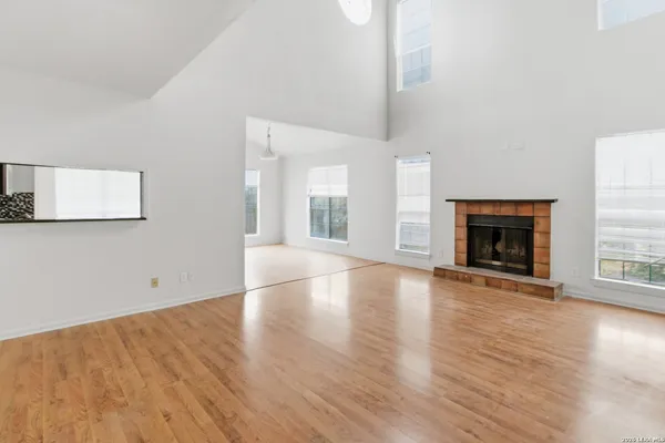 an empty room with wooden floor fireplace and windows