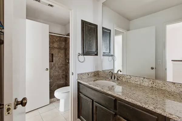 a bathroom with a granite countertop sink a toilet and shower