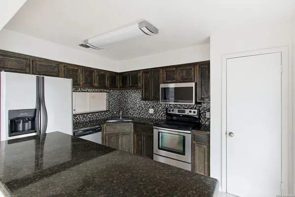 a kitchen with stainless steel appliances granite countertop a stove microwave and refrigerator