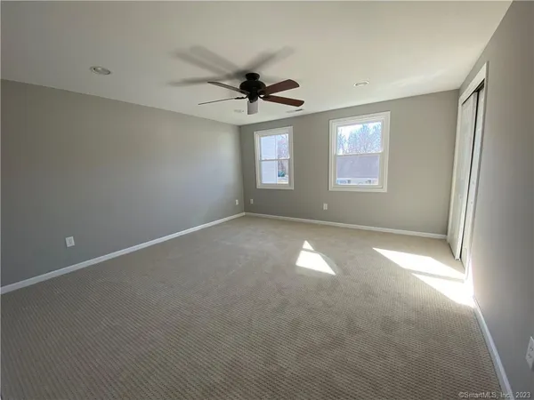 an empty room with windows and fan view