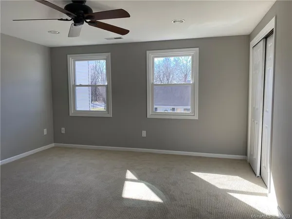 an empty room with windows and fan