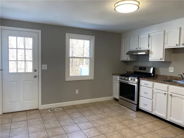 a kitchen with granite countertop a stove a sink and a window