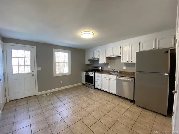 a kitchen with a refrigerator a stove top oven and cabinets