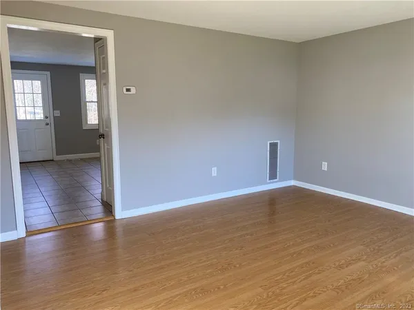 an empty room with wooden floor & windows