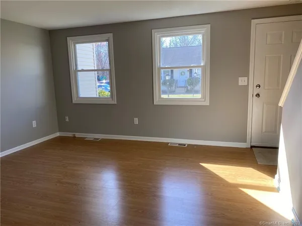 an empty room with wooden floor and windows