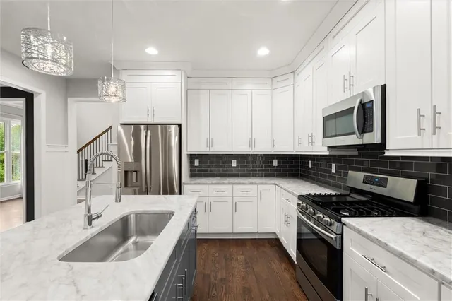 a kitchen with granite countertop a sink a counter top space appliances and cabinets