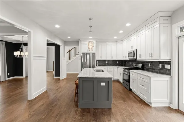 a kitchen with stainless steel appliances granite countertop a refrigerator a sink dishwasher and a stove with wooden floor