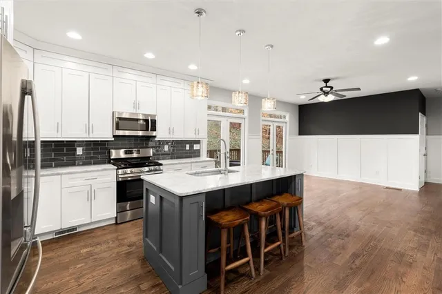 a kitchen with stainless steel appliances a sink a stove a microwave a center island and cabinets