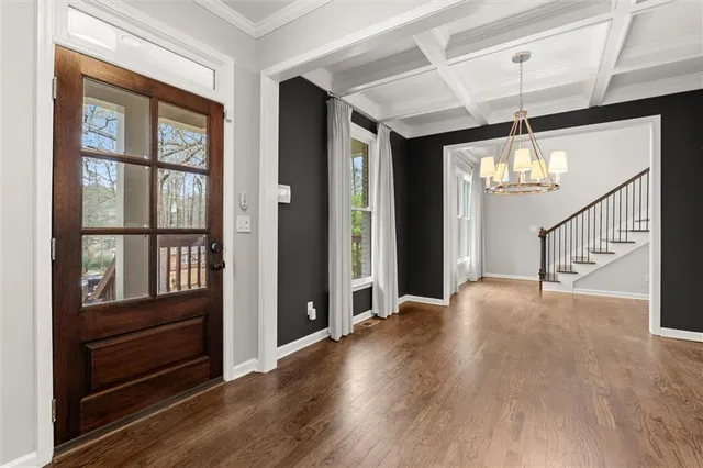 a view of an entryway with wooden floor windows and a chandelier