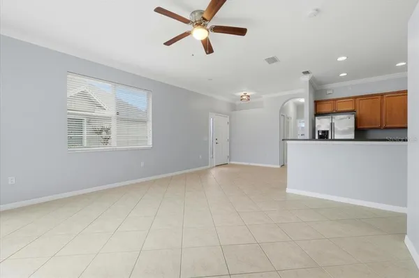 an empty room with kitchen and a ceiling fan