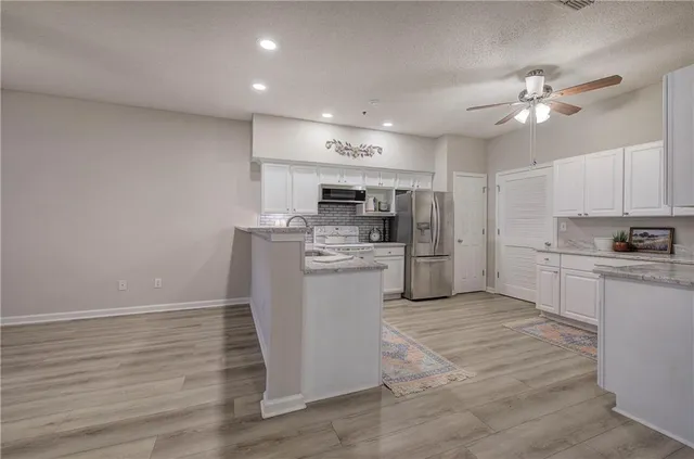 a kitchen with a refrigerator a stove top oven and cabinets