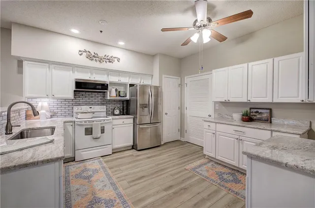 a kitchen with granite countertop a sink stainless steel appliances and white cabinets