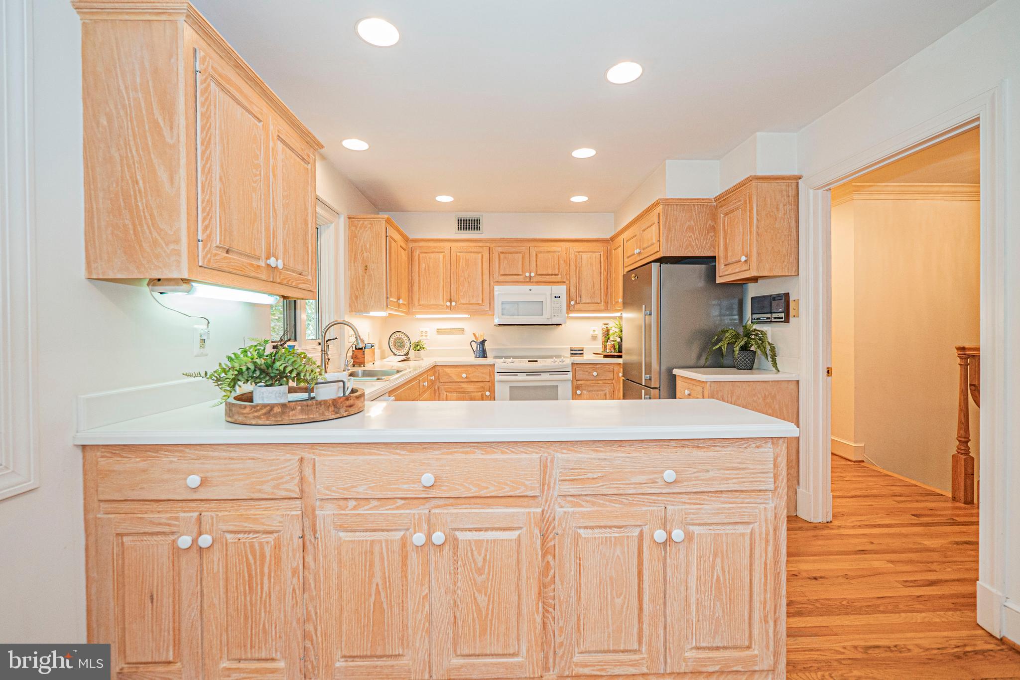 10100 Watkins Road Gaithersburg, MD 20882 - Photo 27 of 113 a kitchen with stainless steel appliances kitchen island granite countertop a refrigerator a sink and white cabinets with wooden floor
