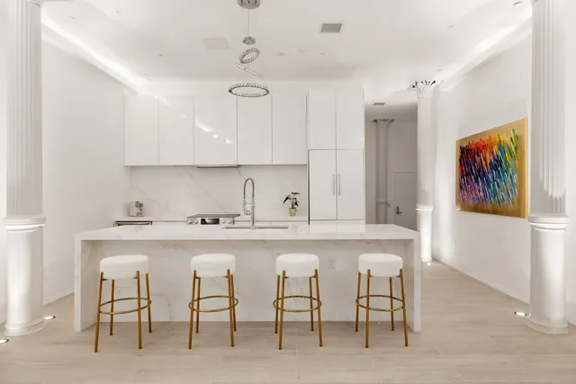 a kitchen with stainless steel appliances a table and chairs in it