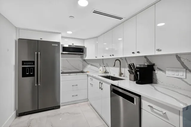 a kitchen with a sink a refrigerator and white cabinets