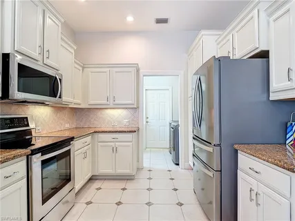 a kitchen with granite countertop a refrigerator stove and microwave