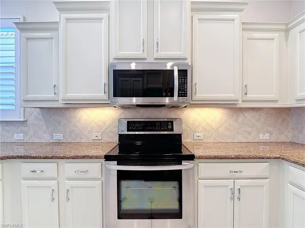 a kitchen with granite countertop white cabinets and a stove top oven