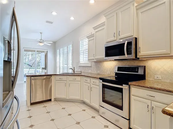 a kitchen with stainless steel appliances granite countertop white cabinets a microwave oven a sink and dishwasher
