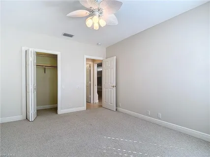 an empty room with a chandelier fan and closet
