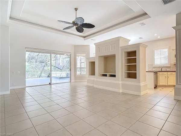 a view of an empty room with a window and kitchen view