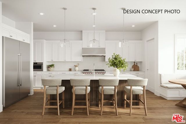 a kitchen with a dining table chairs wooden floor cabinets and stainless steel appliances