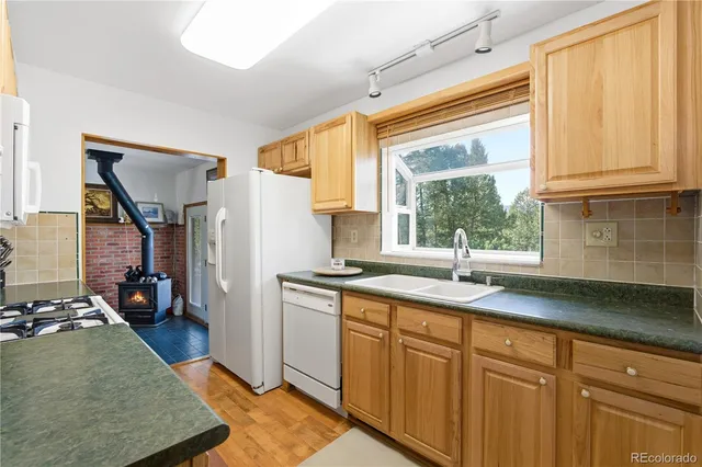a kitchen with granite countertop stainless steel appliances a sink window and cabinets