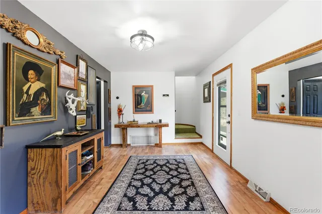 a view of a hallway with wooden floor and furniture
