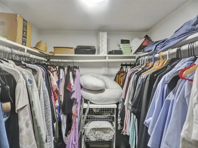 a view of walk in closet with clothes and shoes