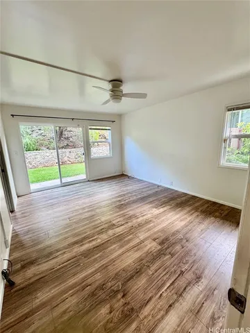 a view of empty room with wooden floor and fan
