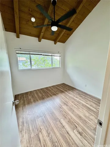 a view of empty room with wooden floor and fan